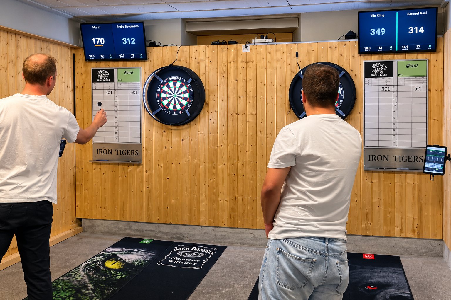 Trainingsabend im Dartlokal: zwei Spieler an zwei elektronischen Dartboards, darüber die DartHub-Anzeigen auf zwei Fernsehern, rechts das Tablet am Board